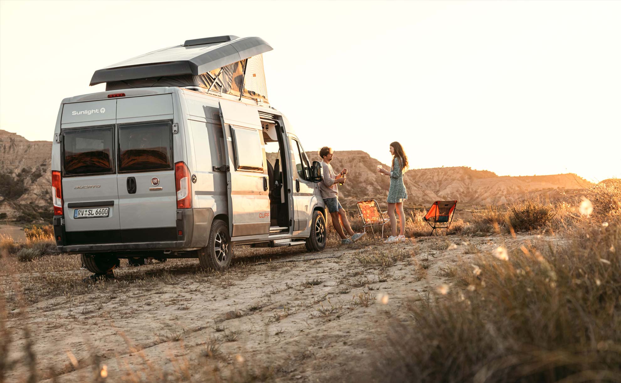 Camper mit einem Pärchen auf einem Feld