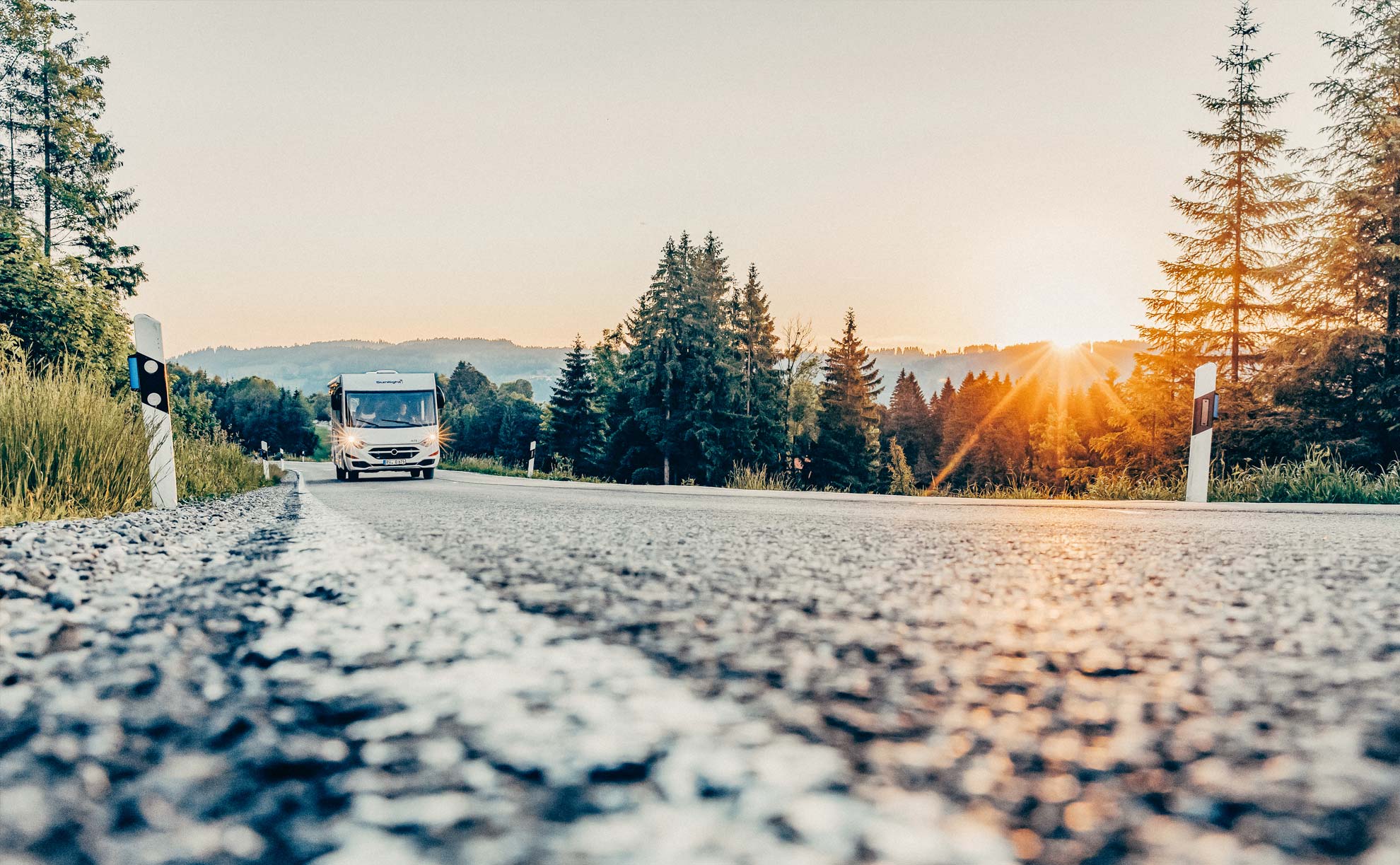 Vollintegriertes Wohnmobil auf einer Landstraße im Sonnenuntergang 