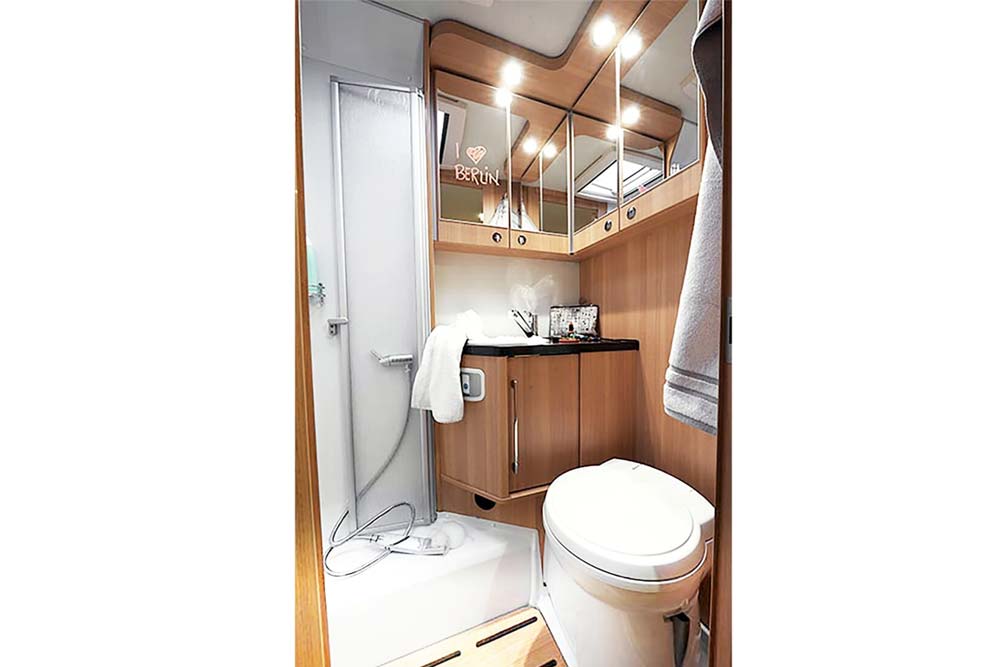 Helles und geräumiges Badezimmer mit getrennter Dusche und WC in einem teilintegrierten Wohnmobil von Roadfans