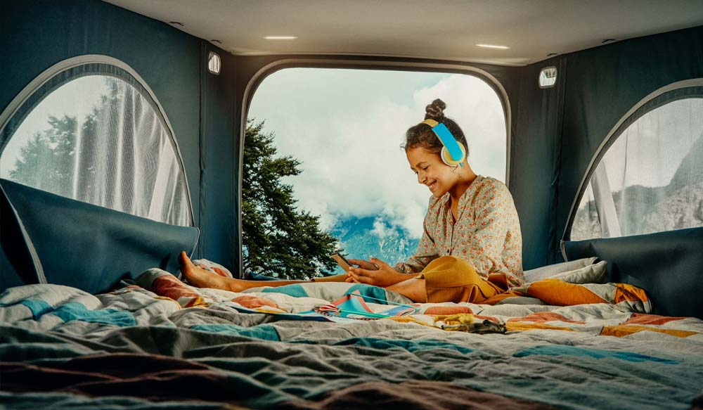 Frau sitzt im Aufstelldach des VW T6.1 California Coast Edition