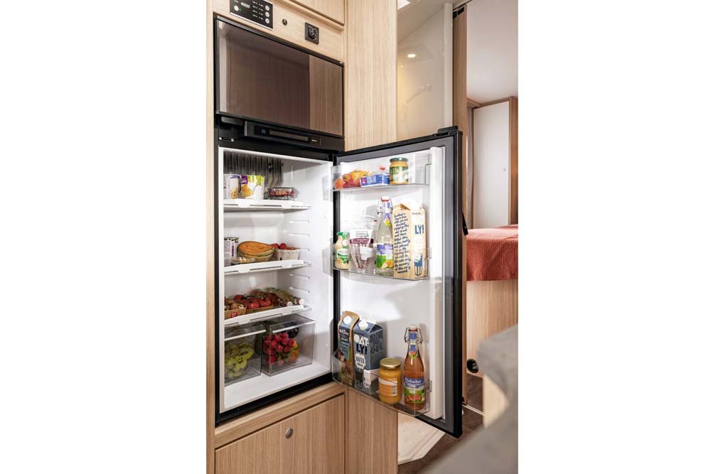 Großer 170 Liter Kühlschrank mit Gefrierfach, gefüllt mit Nahrungsmittel in teilintegrierten Wohnmobil Freedom 4