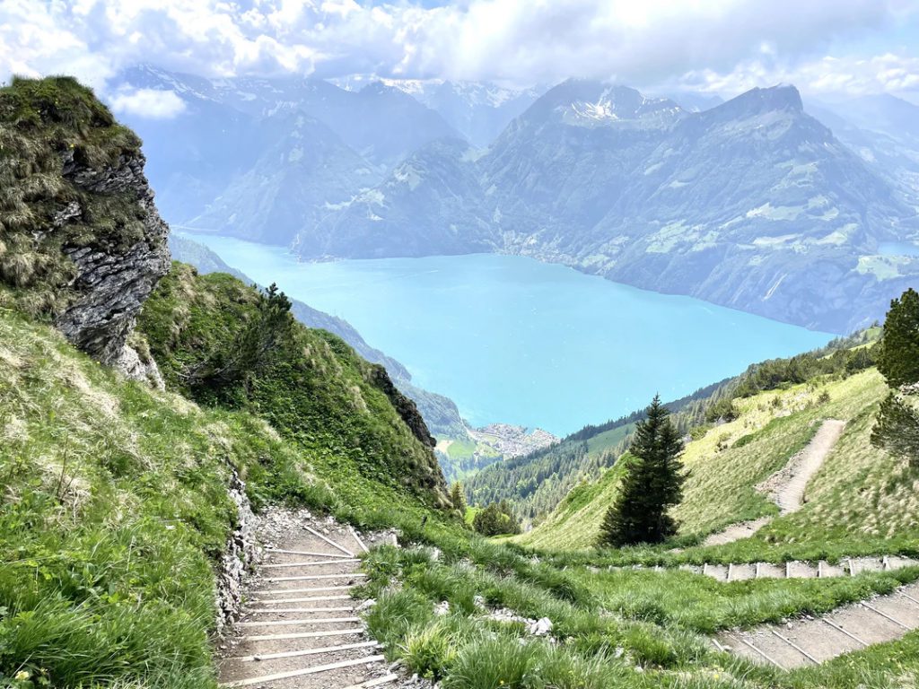 Ausblick auf den kristallklaren Vierwaldstädtersee in der Schweiz, der umgeben von Bergen, Natur und Wolken ist.