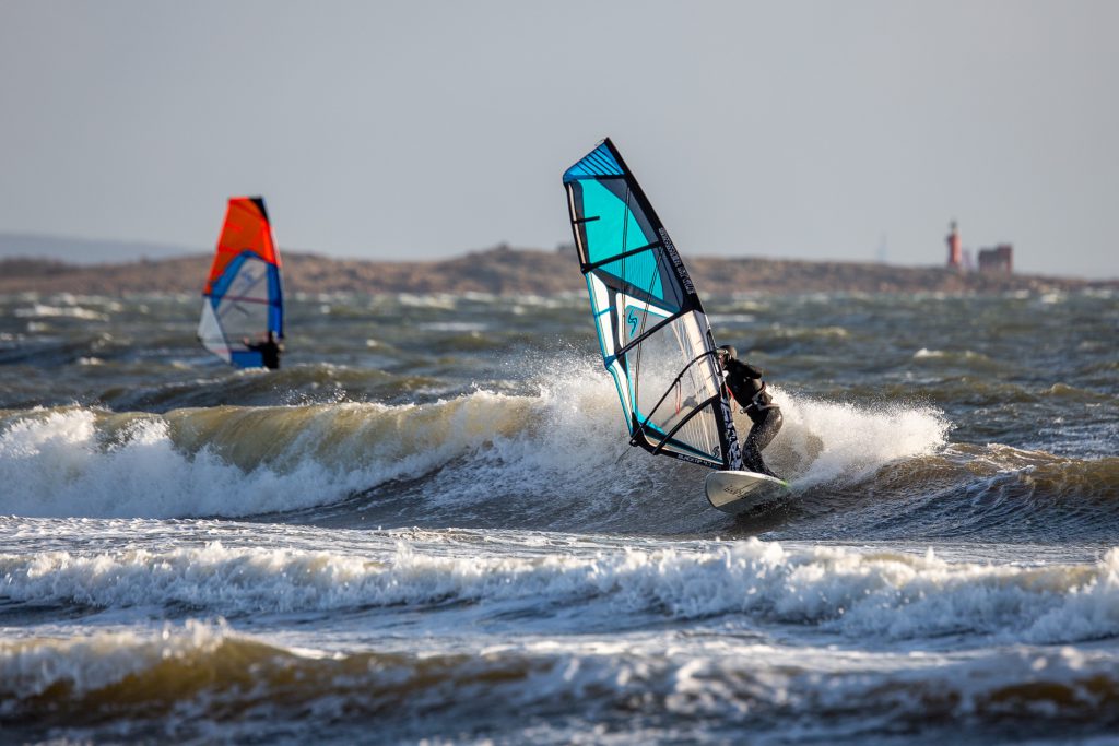 Zwei Windsurfer surfen Wellen