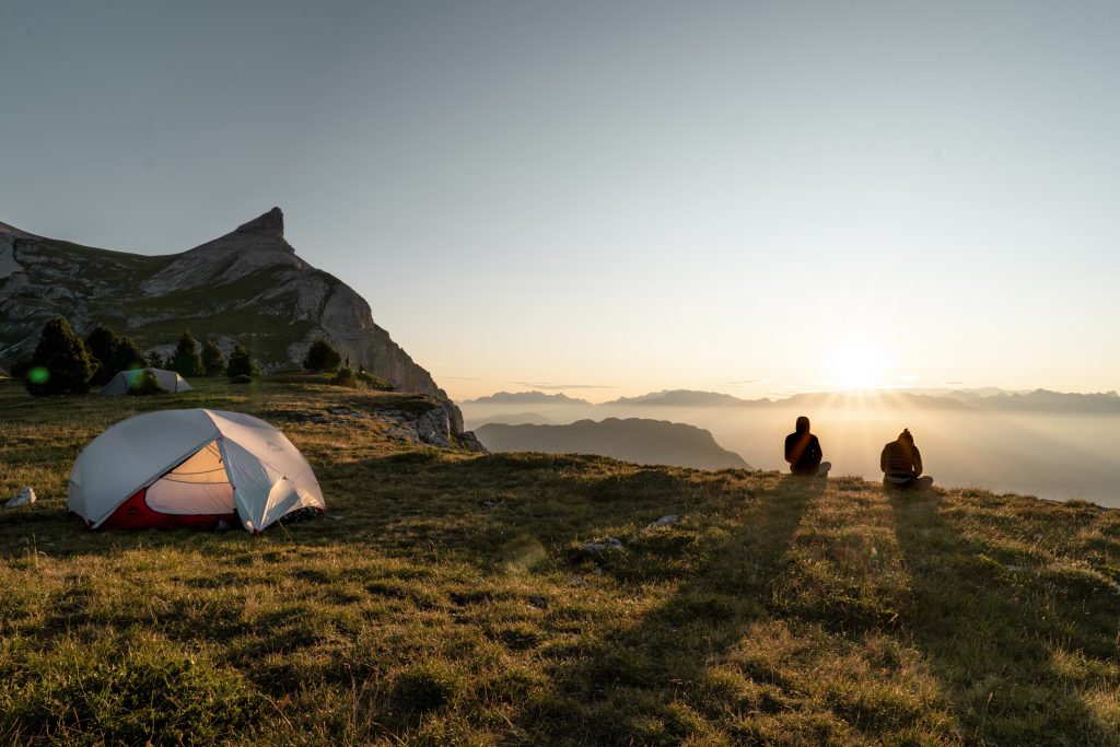 Zwei Personen an einer Klippe mit einem Zelt auf einer Wiese
