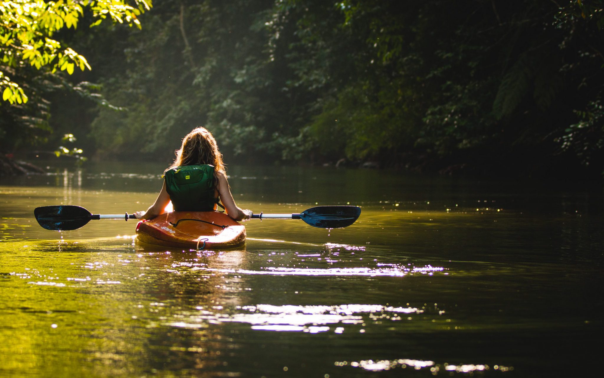 Frau fährt Kanu auf einem See in Waldkulisse