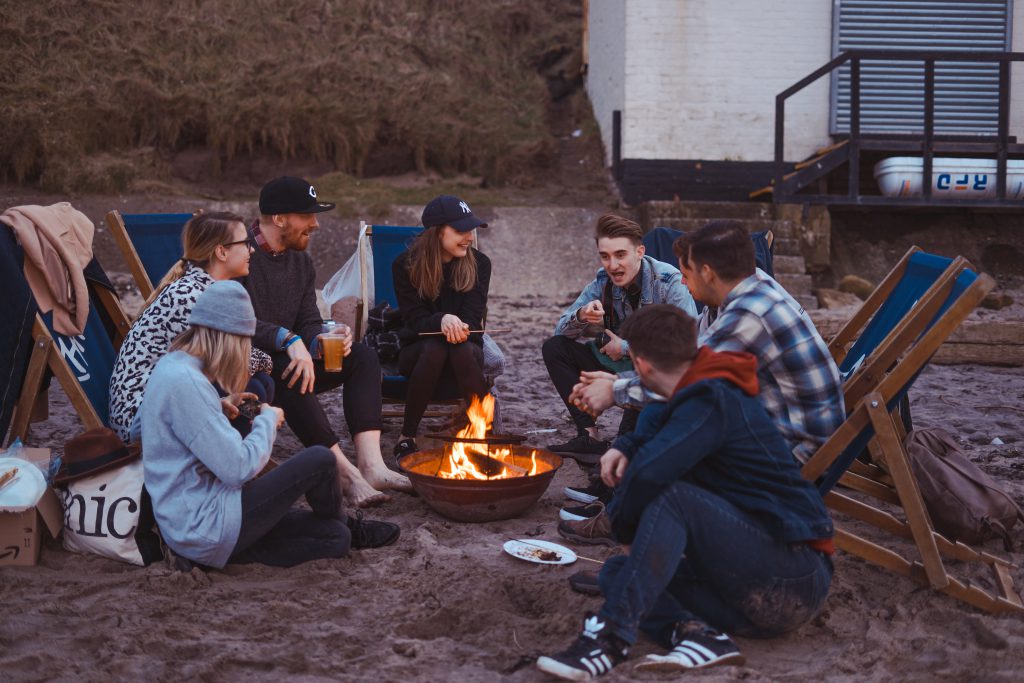 Eine Gruppe jugendlicher sitz am Strand und grillt 