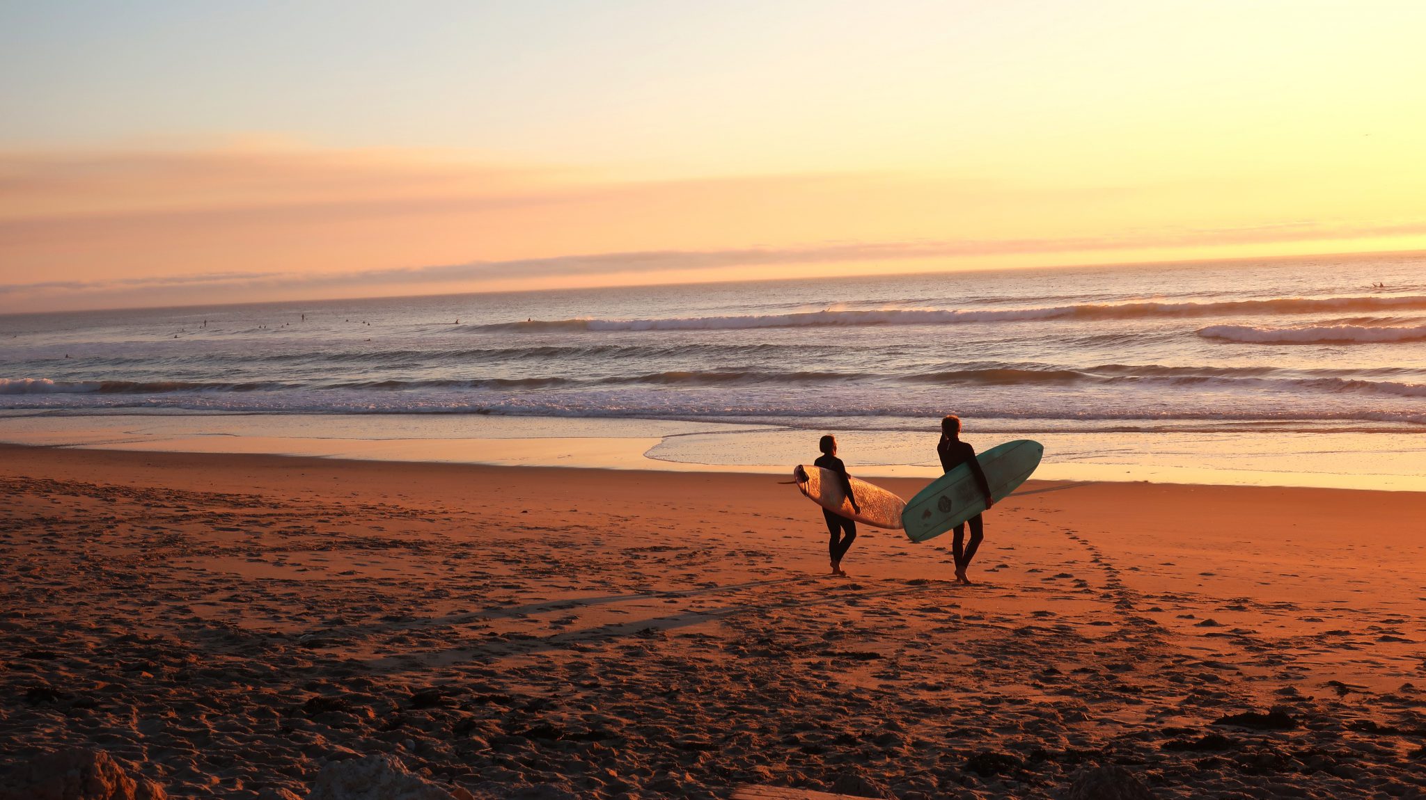 Zwei Surfer am Strand mit Surfbrettern in der Hand