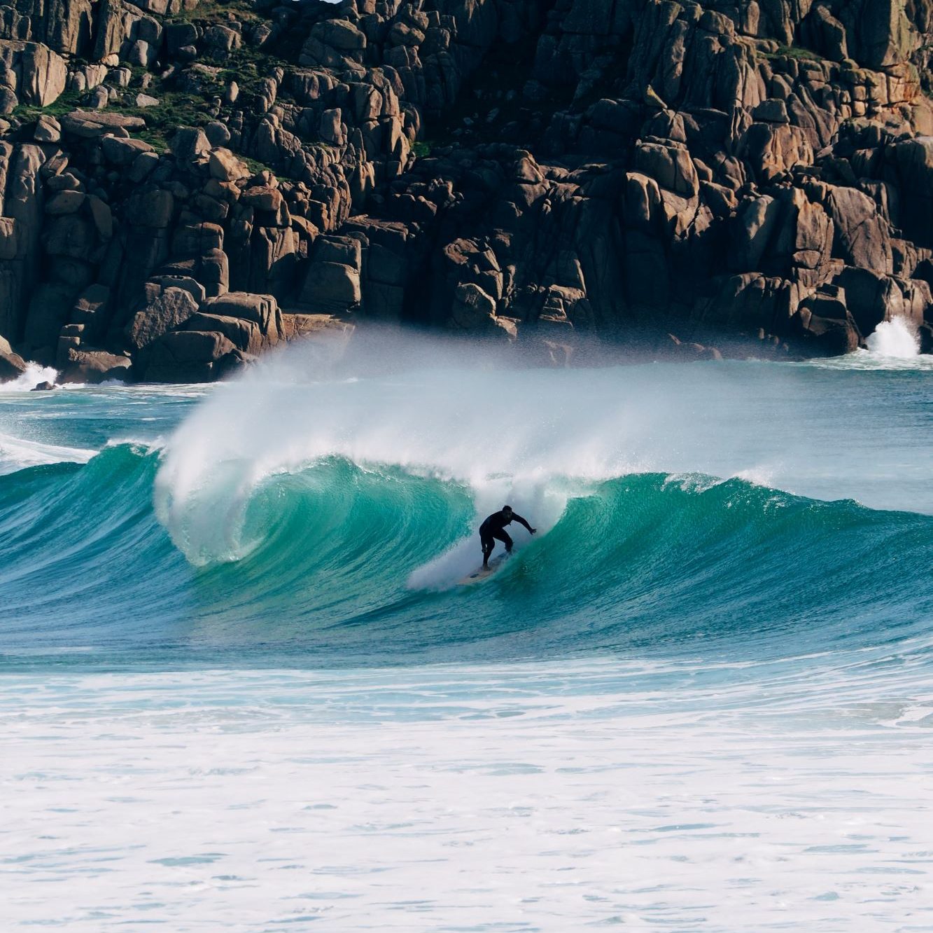 Surfer reitet eine Welle im Hintergrund sind Felsen