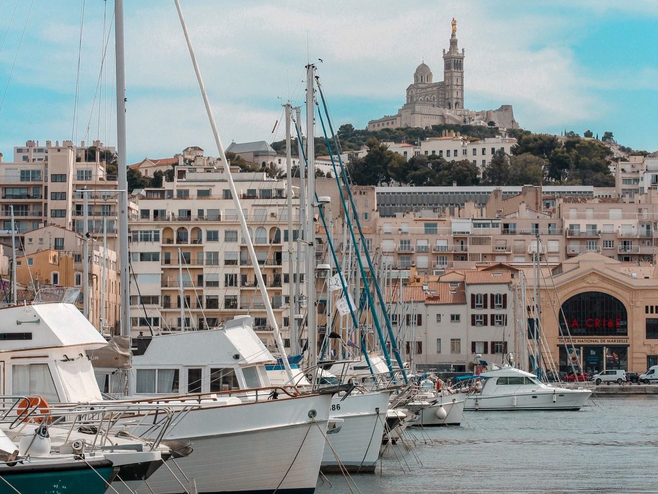 Hafen mit Schiffen, im Hintergrund sieht man die Gebäude der Stadt Marseille