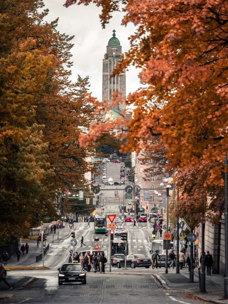 Herbstliche Bäume und eine belebte Starße in Helsinki