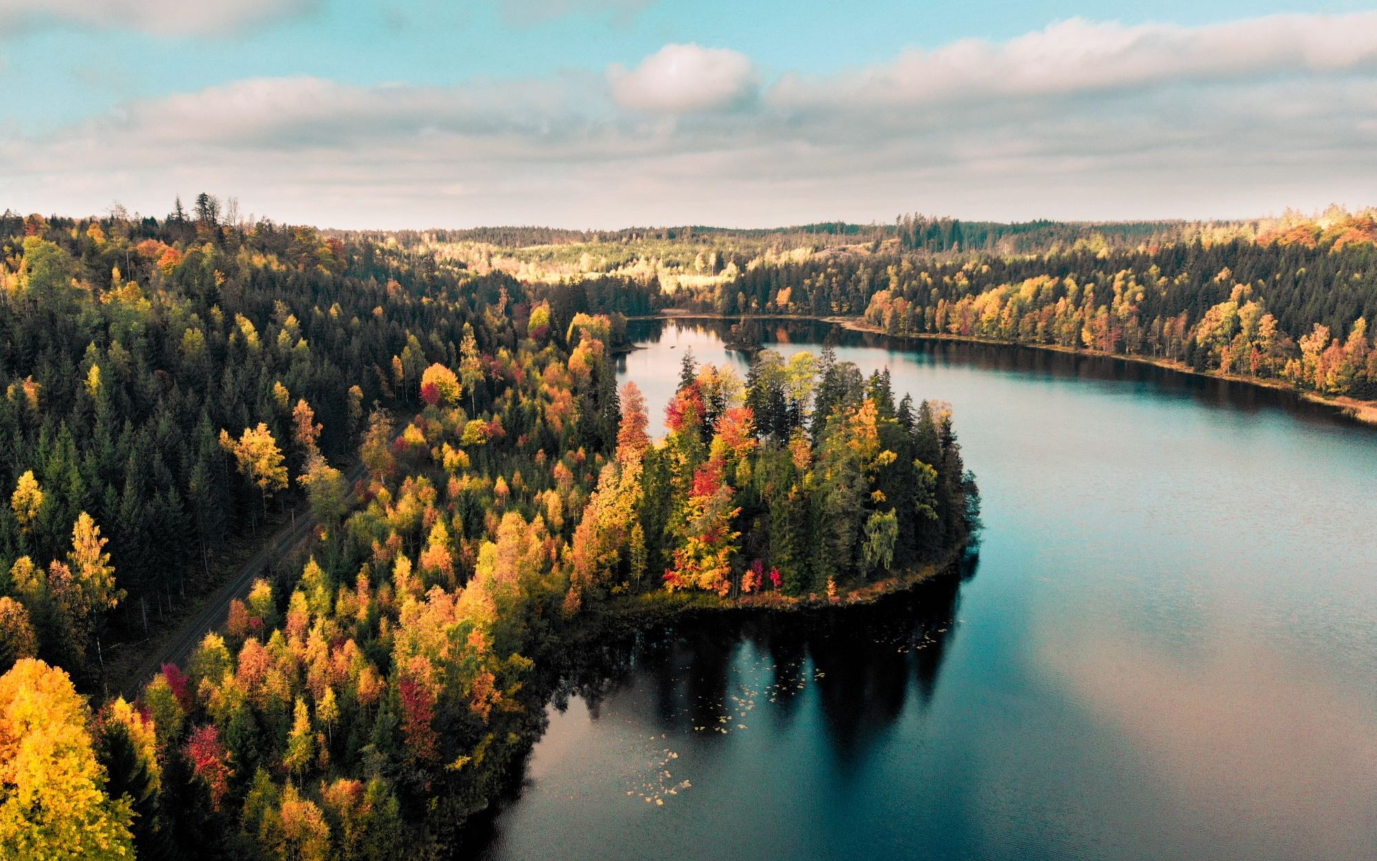 Reiseziele Oktober- See und herbstlicher Wald in Grün und Rottönen
