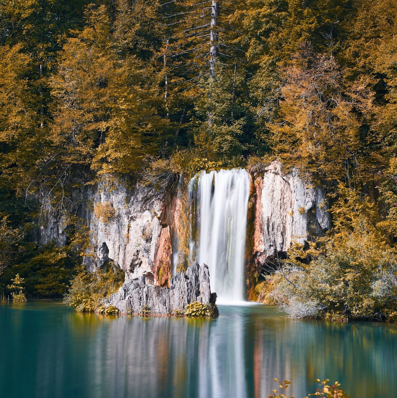 Wasserfall und See in einem herbstlichen Wald