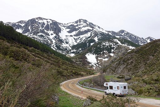 Wo kann man günstig Campen? - Wohnmobil während der Fahrt mit Bergen im Hintergund.