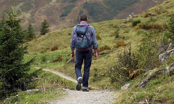 Packliste Wanderurlaub - Blick auf einen Mann mit Rucksack entlang eines Pfades wandern.