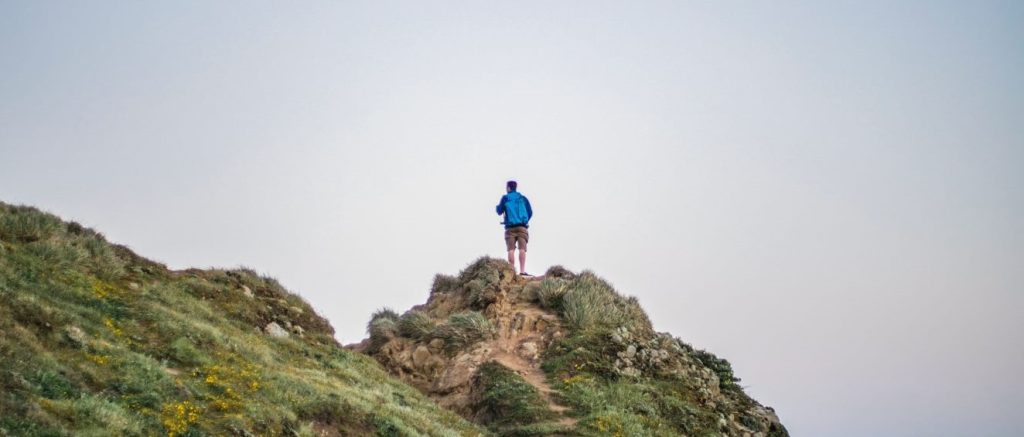 Wanderer mit Rucksack am Gipfel eines Hügels
