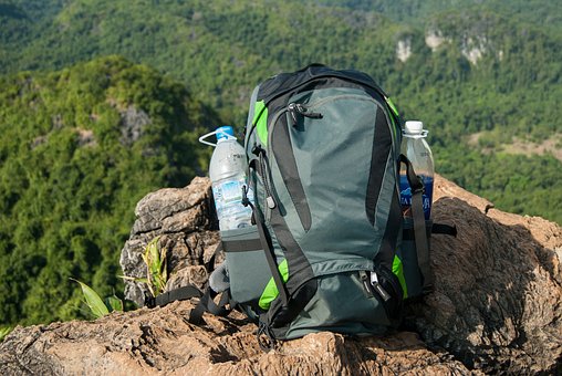 Packliste Wanderurlaub - Blick auf einen Wanderrucksack auf einem Felsen mit Waldbergen im Hintergrund.