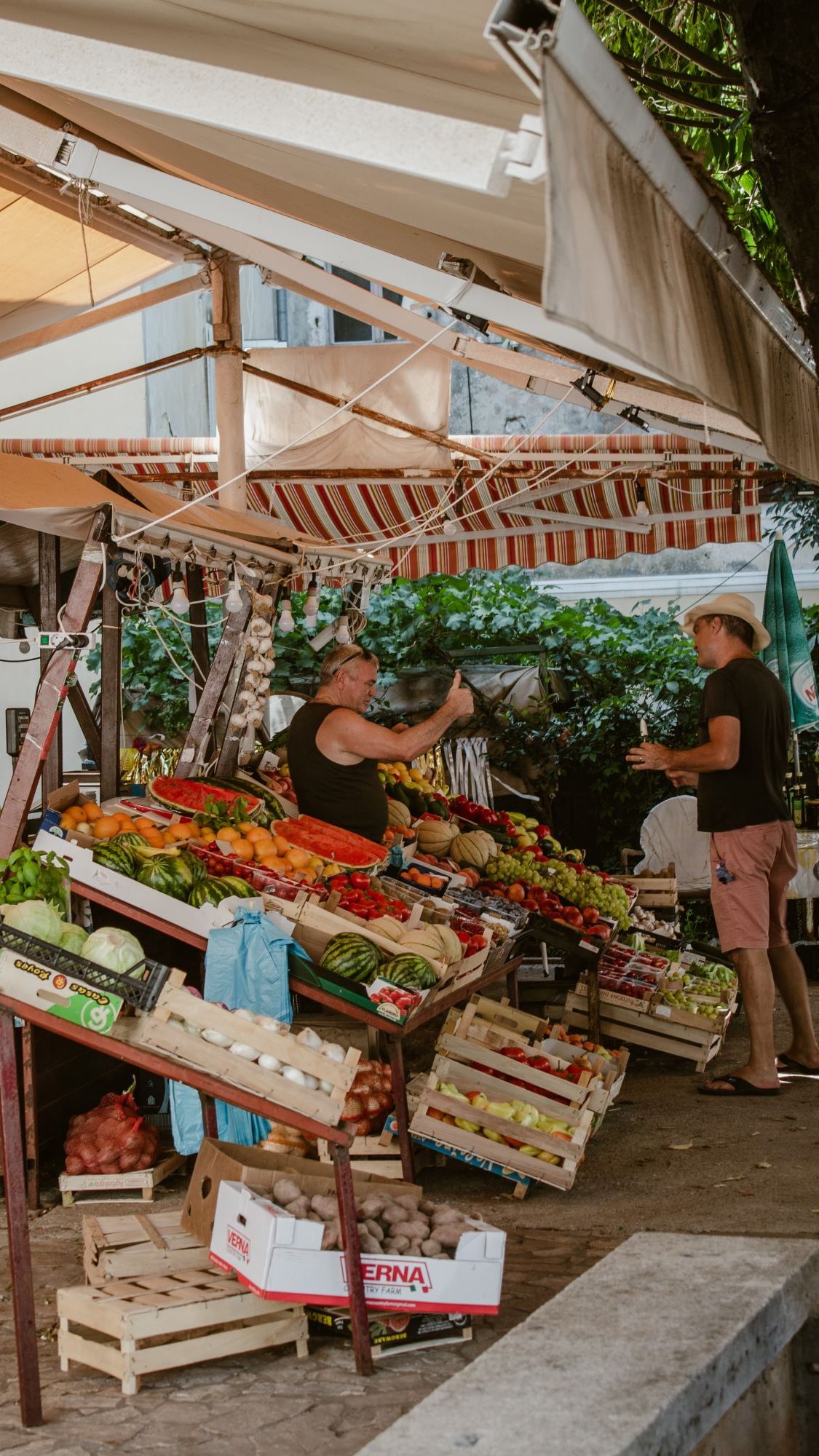 Markt mit frischem Obst und Gemüse. Zwei Männer unterhalten sich