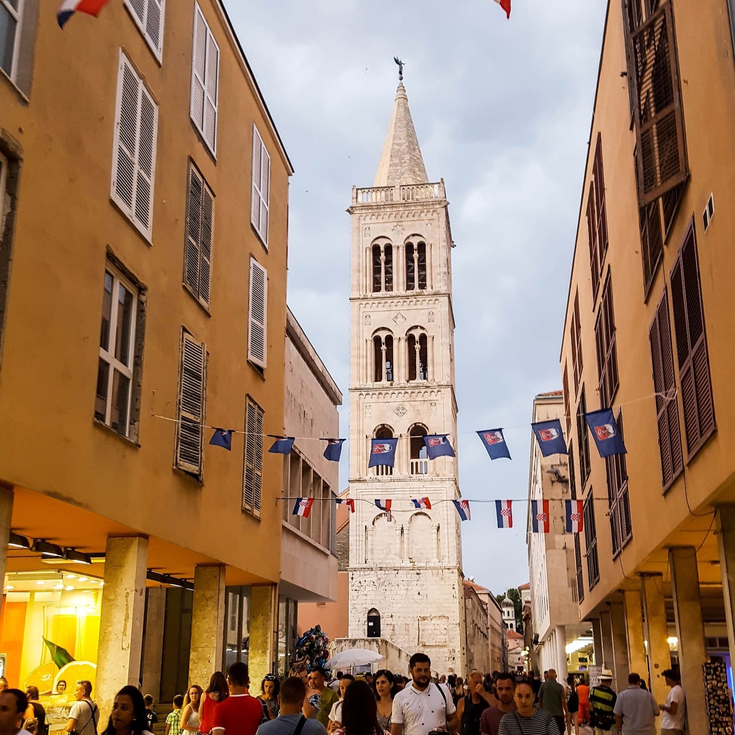 Gasse mit Blick auf den Turm in Zadar. Menschen laufen durch die Straße