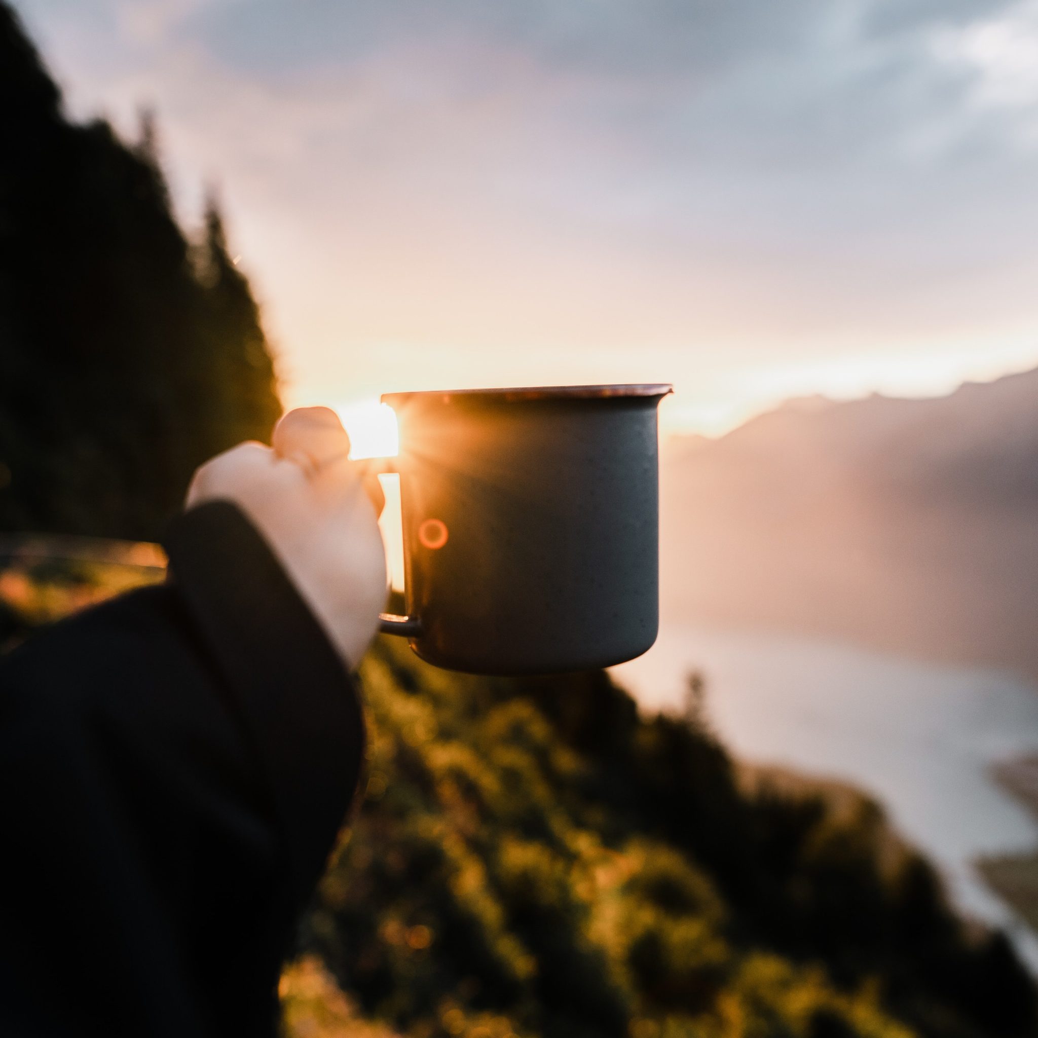 Camp Kaffee - Kaffeetasse und Sonnenaufgang im Hintergrund