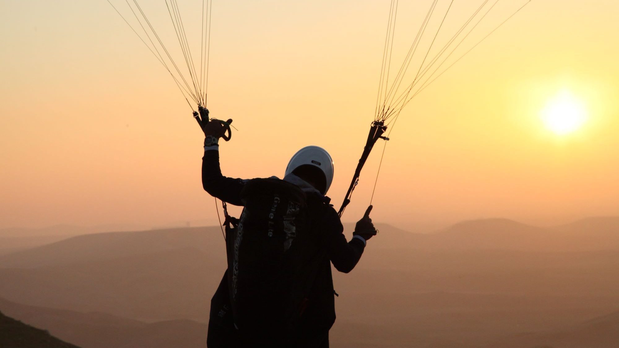 5 Sterne Camping Gardasee - Paragliding. Mann mit Gleitschirm bei Sonnenuntergang