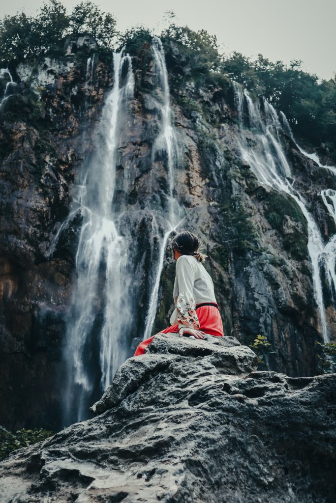 Glamping Kroatien - Frau vor einer Felswand mit vielen kleineren Wasserfällen 