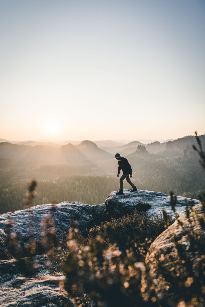 Camping Sächsische Schweiz - Mann auf einem Felsvorsprung. Im Hintergrund die Landschaft der Sächsischen Schweiz im Sonnenuntergang  