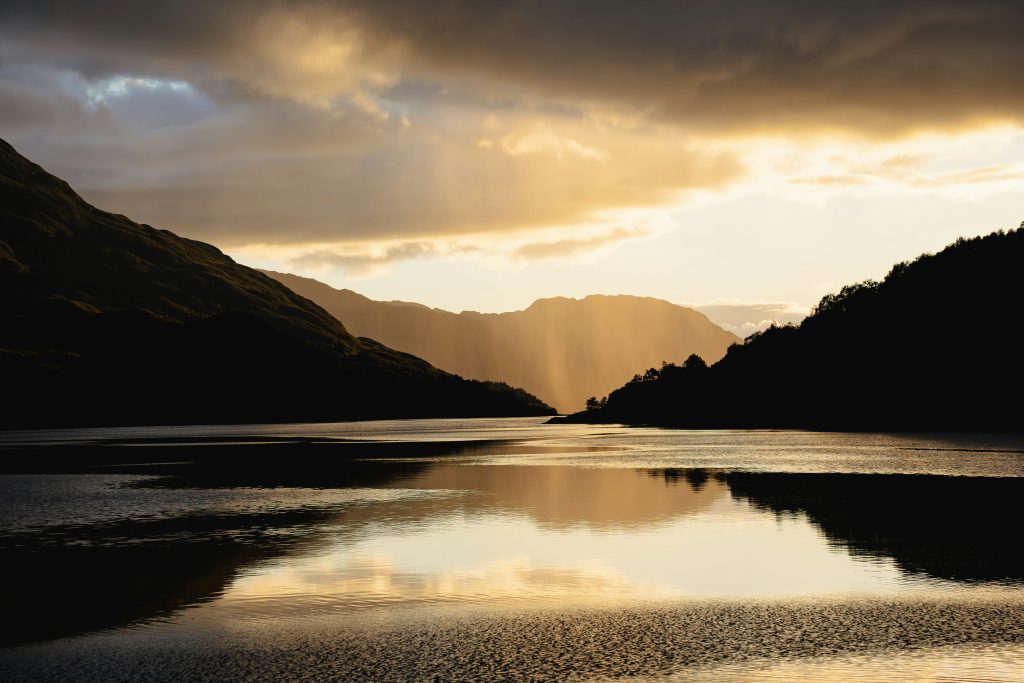 Campingplätze Schottland - Ein See umrandet von Bergen im Sonnenuntergang