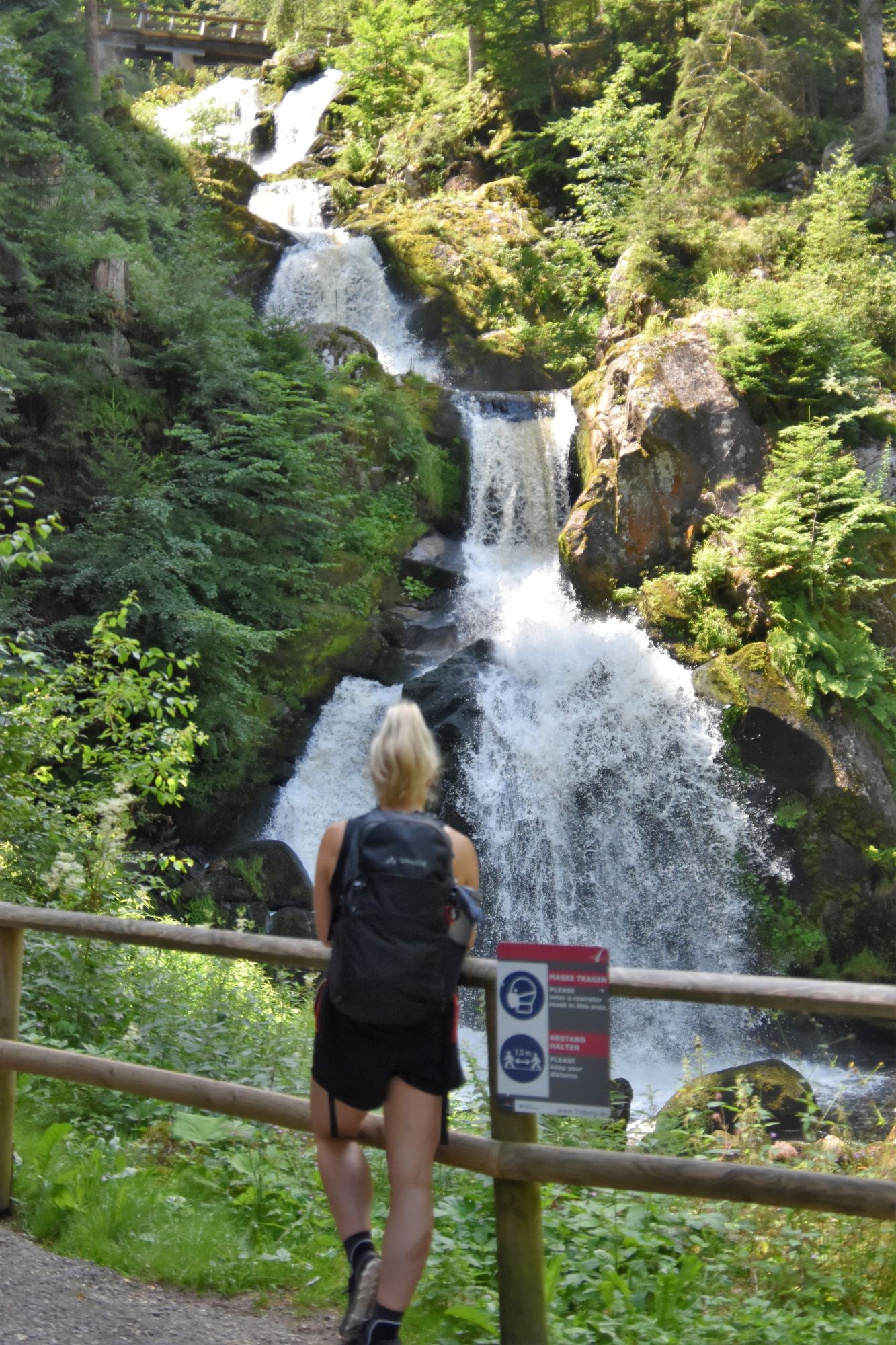 Frau mit Rucksack schaut auf einen Wasserfall