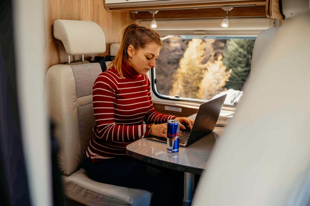 Camping Trends 2024 - Blick auf eine Frau, welche in einem Wohnmobil am Laptop arbeitet.